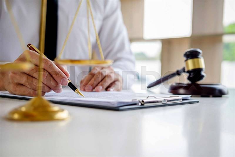Justice and Law concept. Legal counsel presents to the client a signed contract with gavel and legal law or legal having team meeting at law firm in background, stock photo
