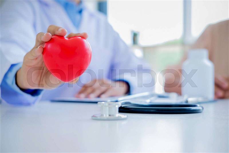 Doctor with stethoscope holding heart. Doctor and patient sitting in the room. Concept healthcare, stock photo