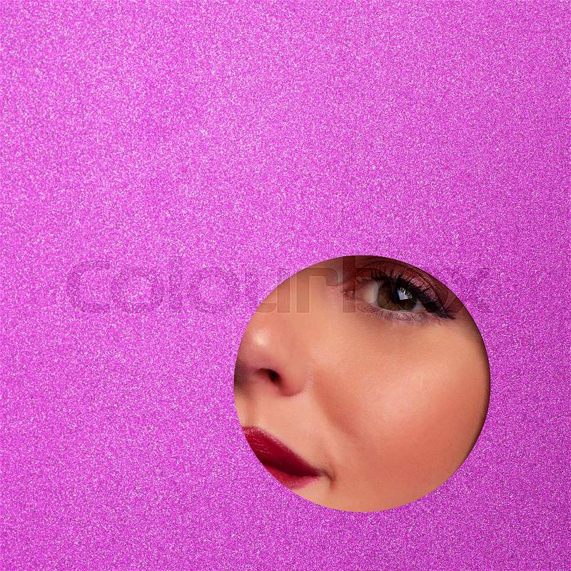 Girl with bright eyes make up looks through hole in violet paper. Business card of artist, beauty concept. Square crop. Cosmetics sale. Beauty salon advertising ..., stock photo