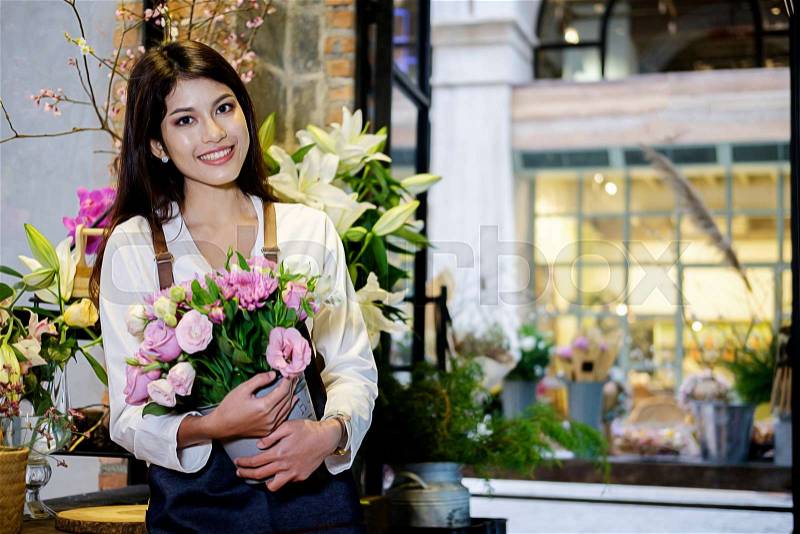 Cheerful charming young business owner flower shop store florist standing and holding flowers, stock photo
