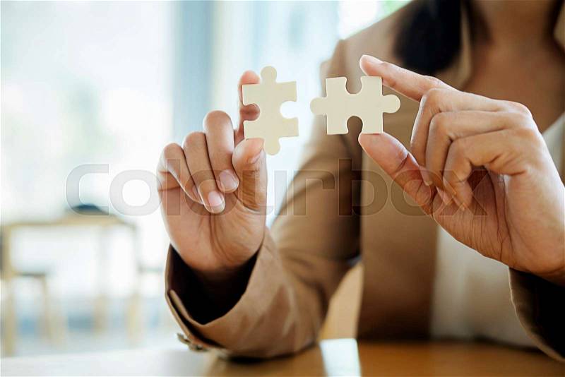 Business woman hands connecting jigsaw puzzle. Business solutions, success and strategy concept. Close up photo with selective focus, stock photo
