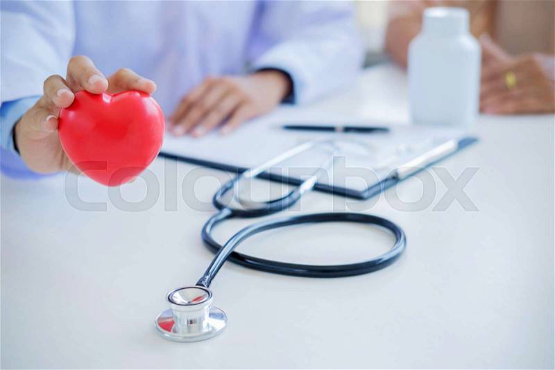 Doctor with stethoscope holding heart. Doctor and patient sitting in the room. Concept healthcare, stock photo
