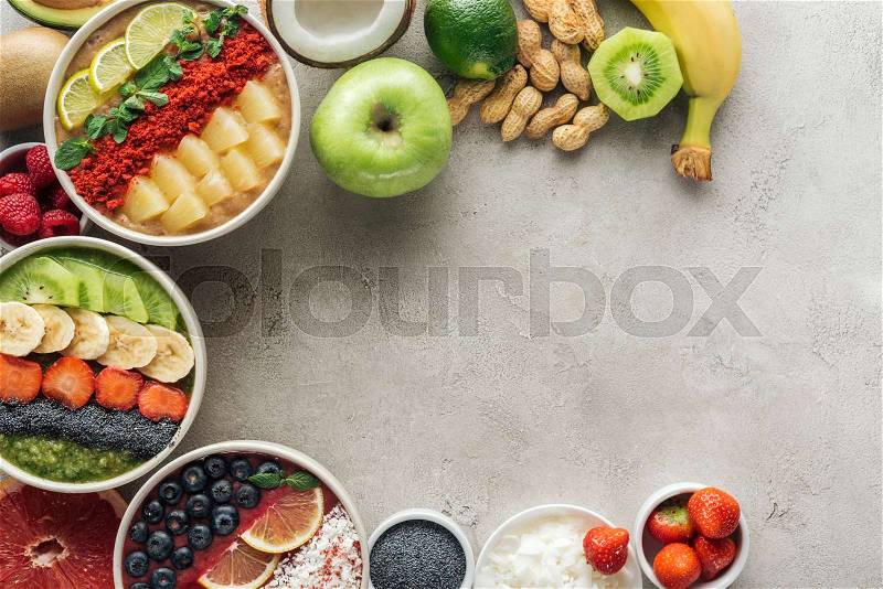 Top view of smoothie bowls with ingredients on grey background with copy space, stock photo