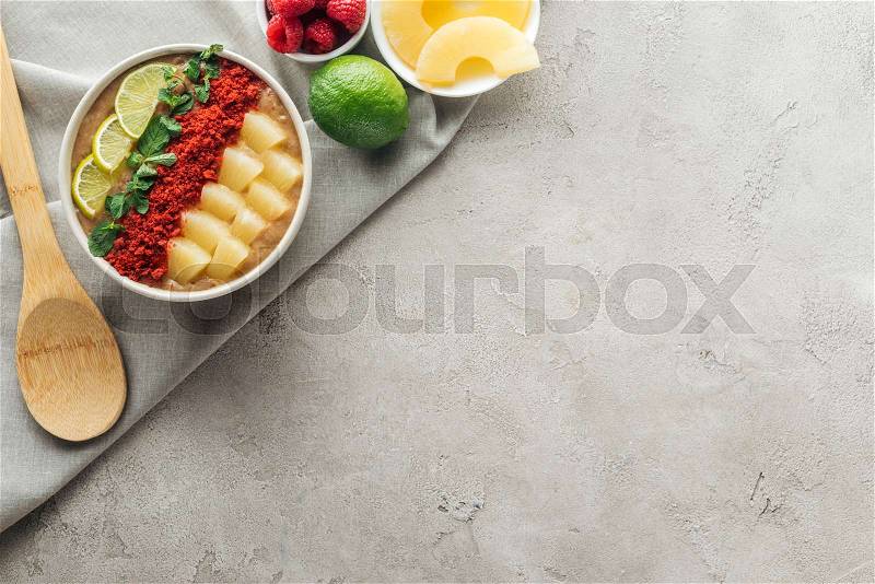 Top view of delicious smoothie bowl with ingredients on grey background with copy space, stock photo