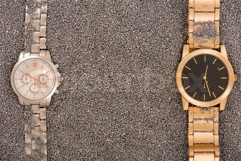 Top view of luxury watches lying on golden sand , stock photo