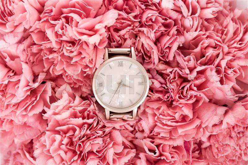 Top view of luxury swiss wristwatch lying on blooming flowers, stock photo
