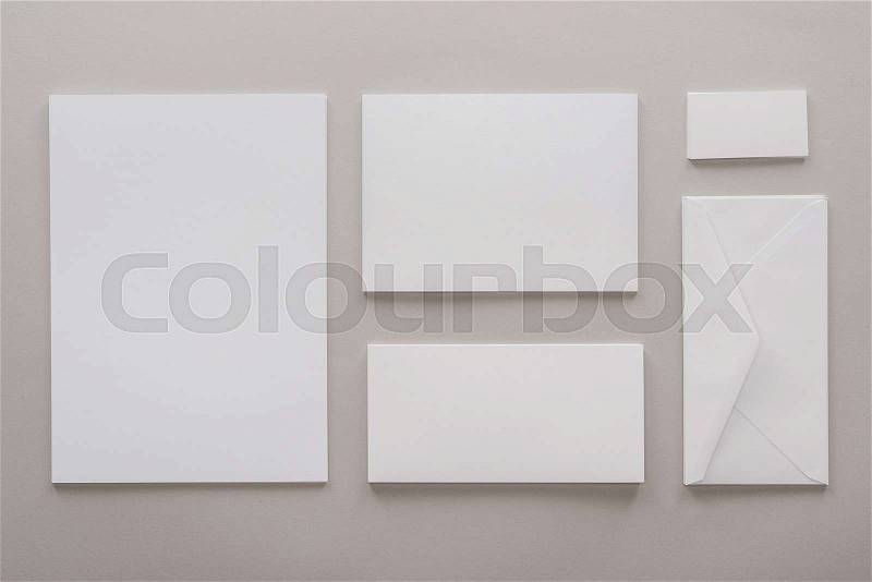 Top view of empty papers and envelope with copy space on grey background, stock photo