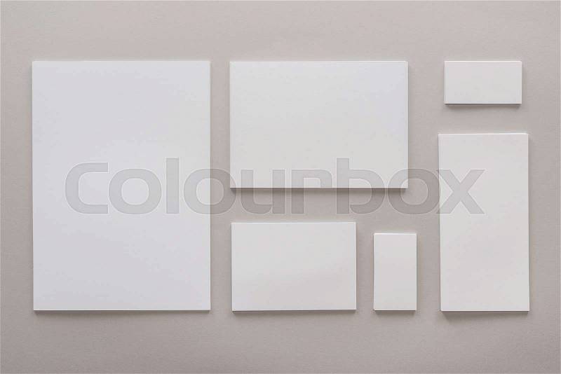 Top view of empty papers and cards with copy space on grey background, stock photo
