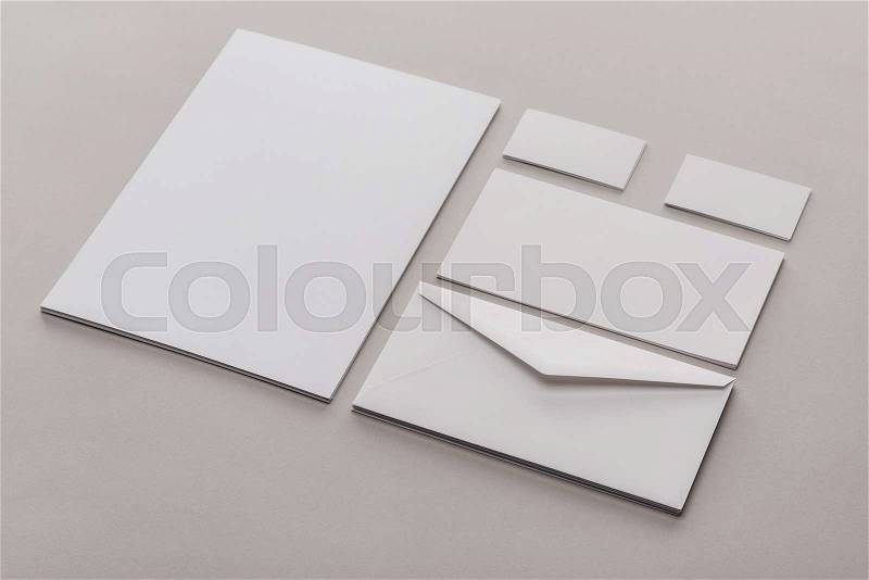 Flat lay with white empty papers and envelopes on grey background, stock photo