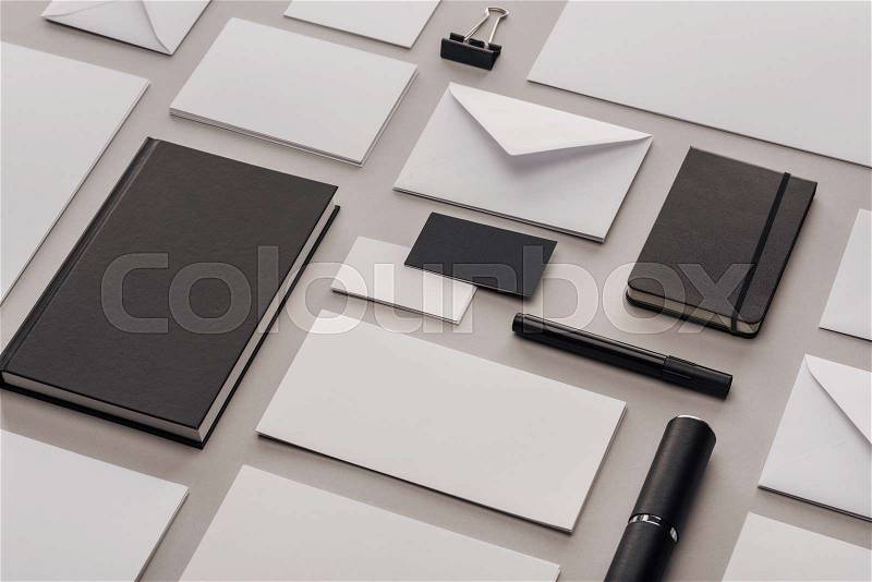 Flat lay with white empty papers and black office supplies on grey background, stock photo