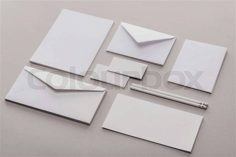 Flat lay with envelopes, cards, sheets of paper and pencils on grey background, stock photo
