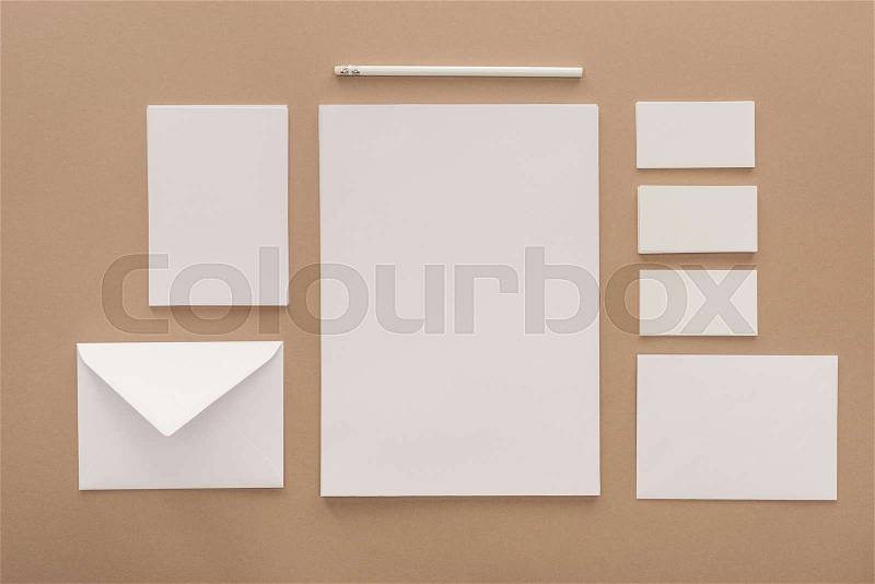Envelope, pencil, cards and sheets of paper on beige background, stock photo