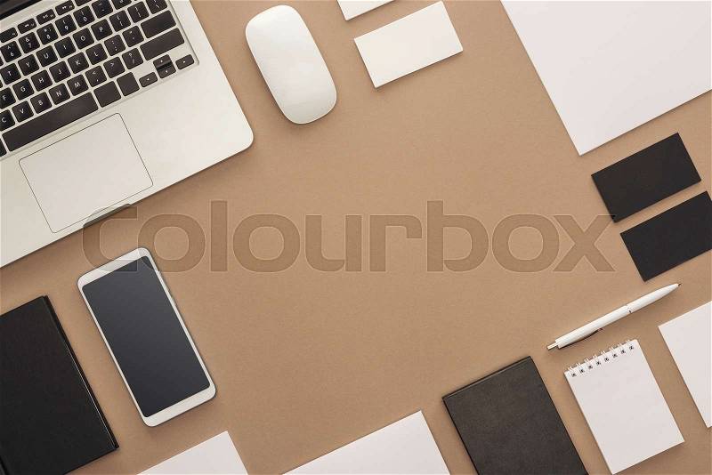 Laptop, smartphone, pen, computer mouse, cards and notebooks on beige background, stock photo