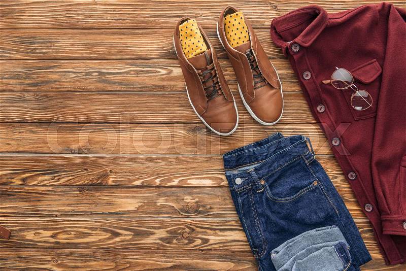 Flat lay with boots, shirt and jeans on wooden background, stock photo
