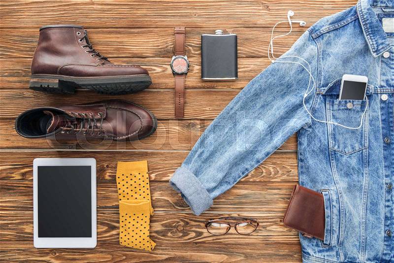 Flat lay of boots, denim jacket and digital devices on wooden background, stock photo