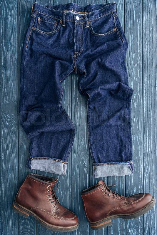 Top view of denim pants and leather boots on wooden background, stock photo