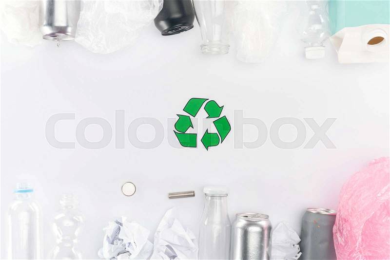 Top view of cans, plastic and glass bottles, batteries, paper, recycling sign, carton bottle and pink plastic bag, stock photo
