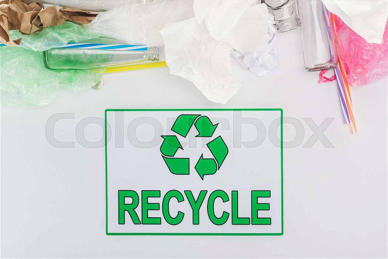 Glass bottles, plastic bags, paper and plastic tubes with recycling sign on grey background, stock photo