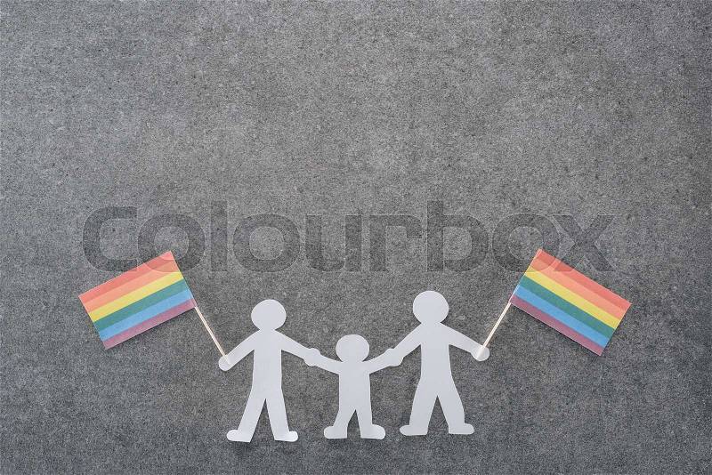 White paper cut same sex family with rainbow flags on grey background, lgbt concept, stock photo