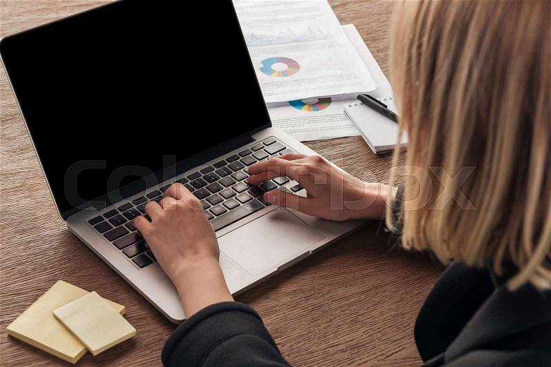 Partial view of blonde woman typing on laptop keyboard, stock photo