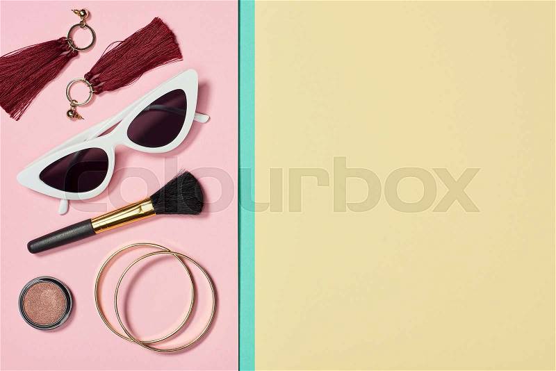 Flat lay with lipstick, bracelets, earrings, cosmetic brush, sunglasses and blush, stock photo