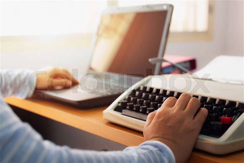 Hands of woman typing both typewriter and laptop on working desk in office. Education concept, stock photo
