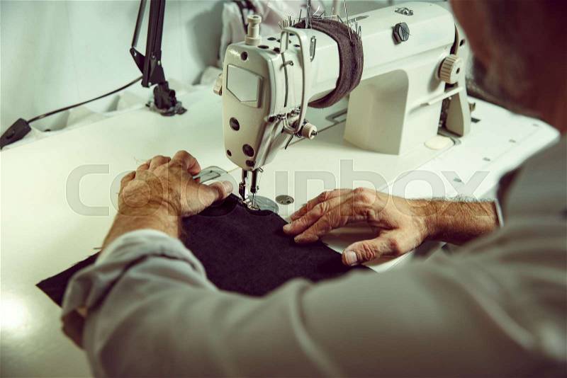 Man\'s hands behind sewing. Leather workshop. Textile vintage industrial. The man in female profession. Gender equality concept, stock photo