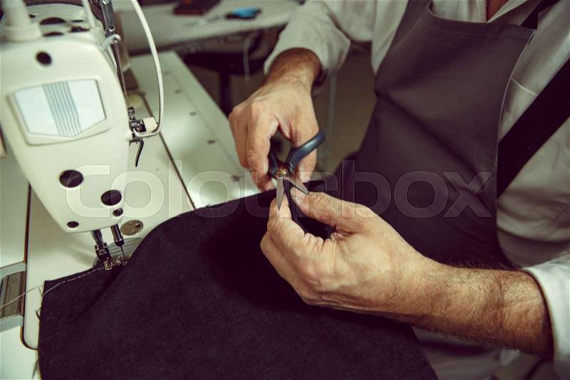 Man\'s hands and sewing machine. Leather workshop. Textile vintage industrial. The man in female profession. Gender equality concept, stock photo
