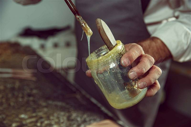 Shoemaker makes shoes for men. He smears special liquid with a brush. The man in female profession. Gender equality concept, stock photo