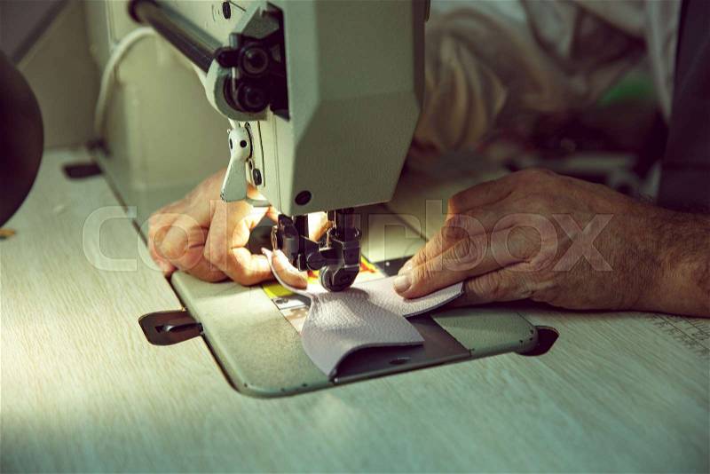 Man\'s hands behind sewing. Leather workshop. Textile vintage industrial. The man in female profession. Gender equality concept, stock photo