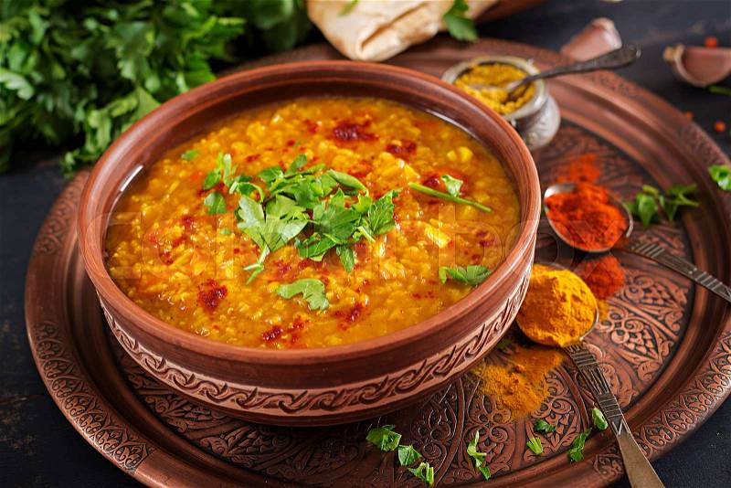 Indian dal. Traditional Indian soup lentils. Indian Dhal spicy curry in bowl, spices, herbs, rustic black wooden background. Authentic Indian dish. Overhead, stock photo