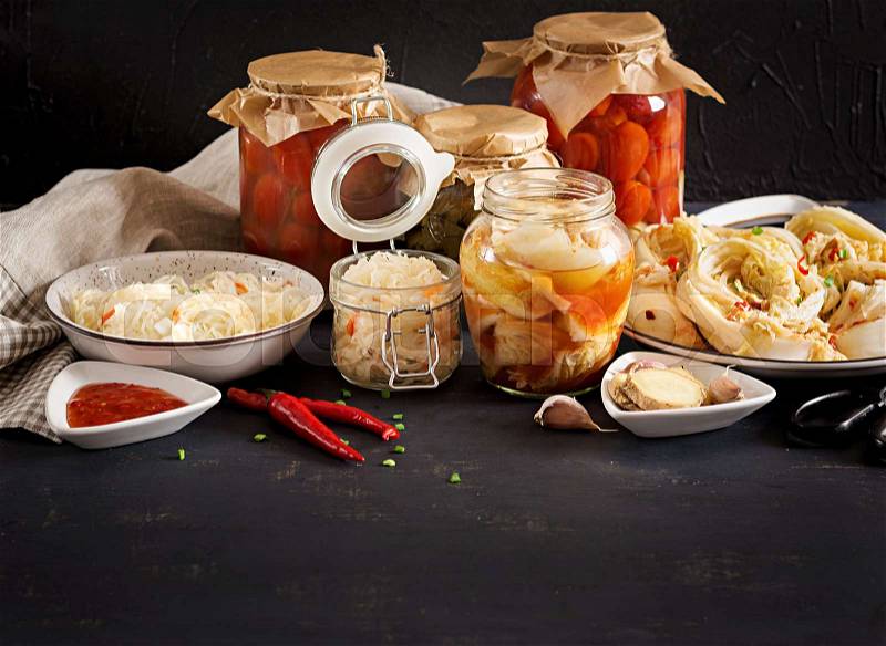 Fermented food. Vegetarian food concept. Cabbage kimchi, tomatoes marinated, sauerkraut sour glass jars over rustic kitchen table. Canned food concept. Copy space, stock photo