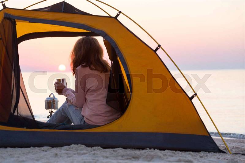 Happy weekend by the sea - girl in a tent on the beach at dawn. Ukrainian landscape at the Sea of Azov, Ukraine, stock photo