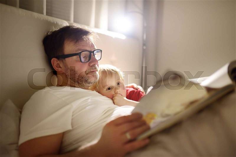 Father reading bedtime stories to child. Dad putting son to sleep. Quality family time, stock photo