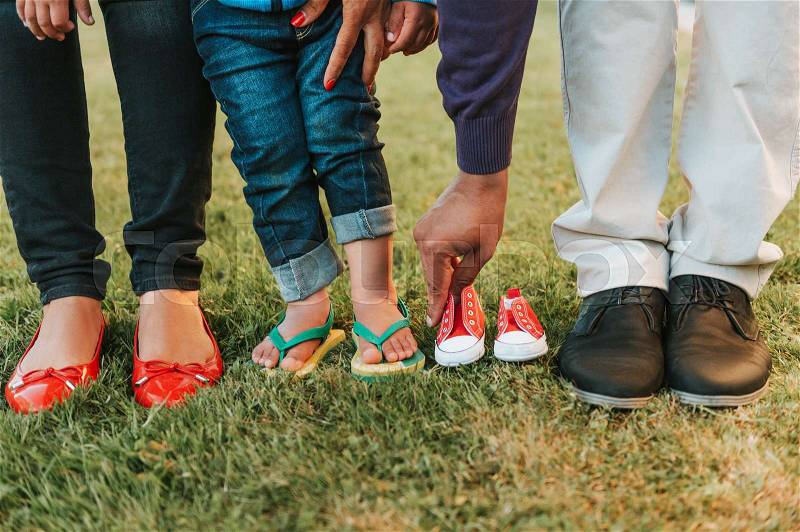 Family feet and legs posing for baby announcement, stock photo