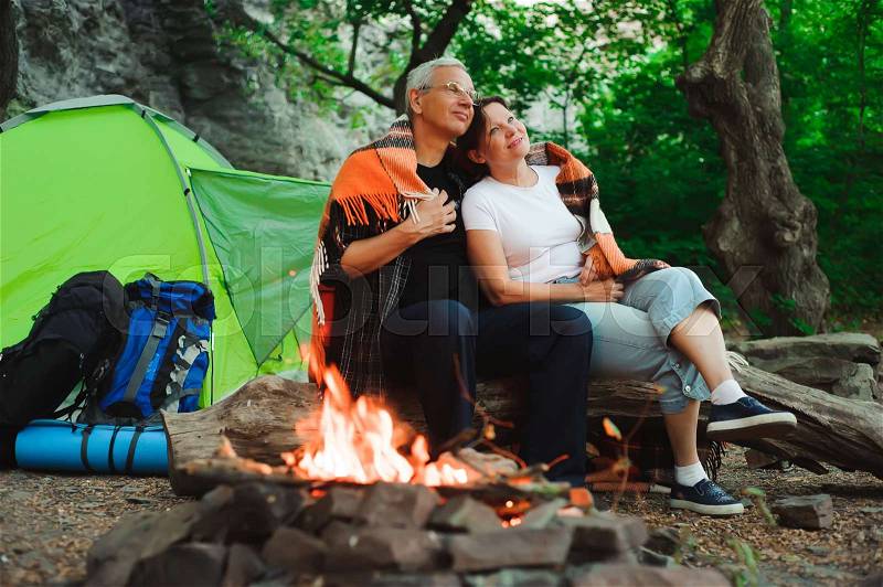 Tent camping couple romantic sitting by bonfire night countryside, stock photo