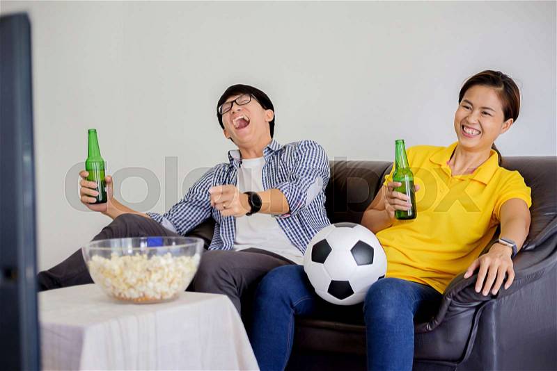 People watch soccer. Asian football supporters watching soccer on television at home with happy emotion, stock photo