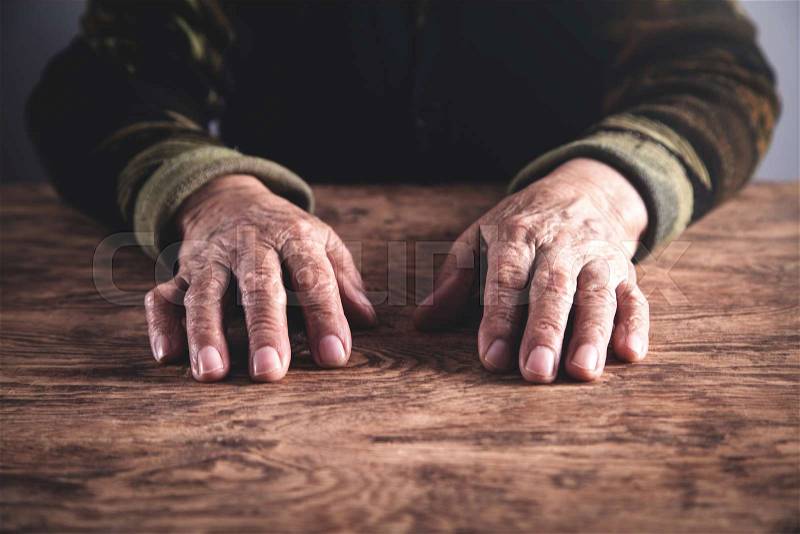 Old woman hands on wooden table, stock photo