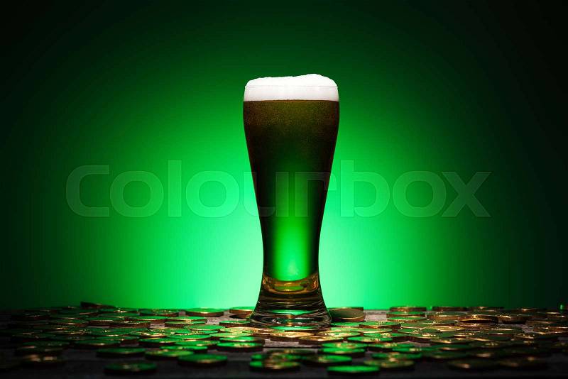 Glass of irish beer standing on wooden table on green background, stock photo