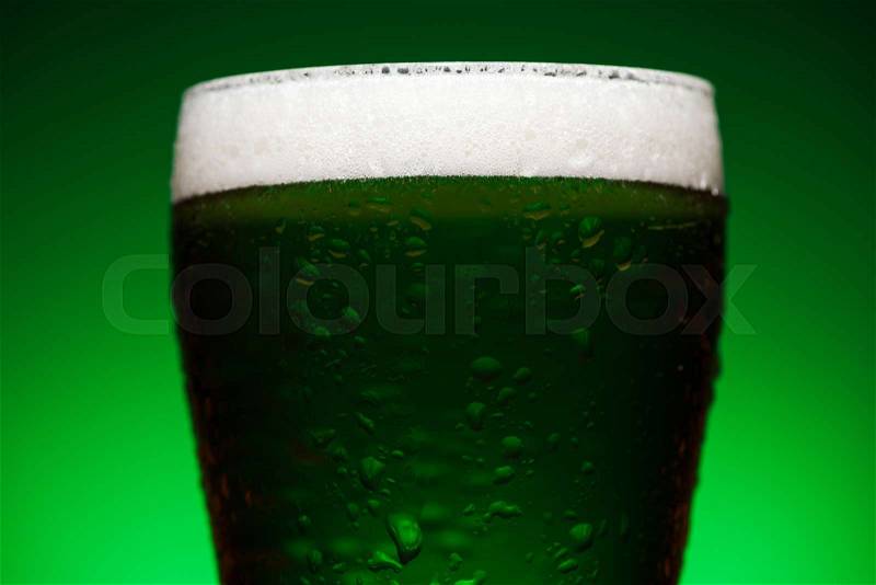 Close up of glass of green irish ale isolated on green , stock photo