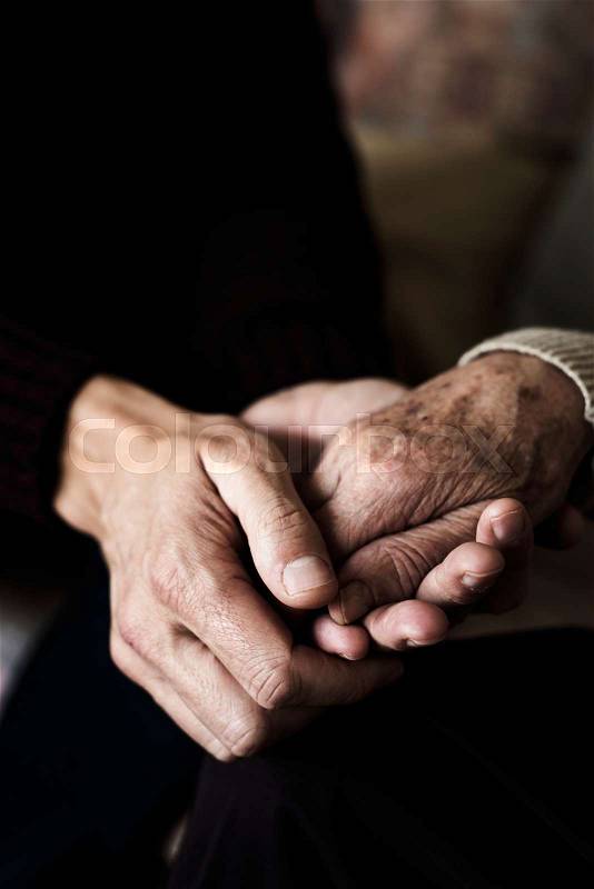 Closeup of a young caucasian man holding the hand of an old caucasian woman with affection, stock photo