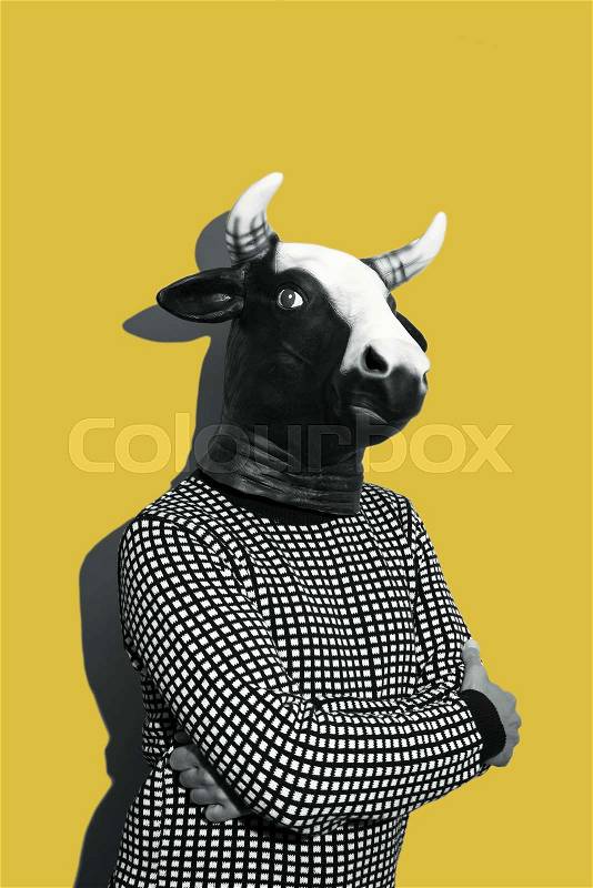 Young caucasian man with a cow mask, in black and white, on a yellow background with some blank space on top, stock photo