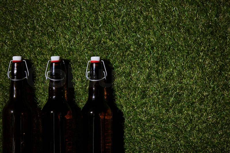Top view of brown bottles with beer lying on grass, stock photo