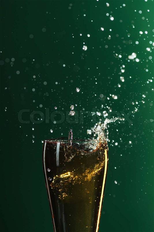 Glass of cold beer with splashes isolated on green, st patrick day concept, stock photo