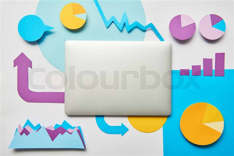 Top view of laptop, charts and graphs, pointers made of paper on white background , stock photo