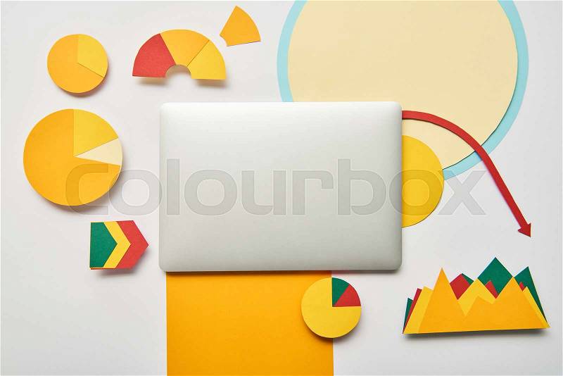 Top view of laptop with paper charts and graphs, pointers, sheet of paper on white background, stock photo