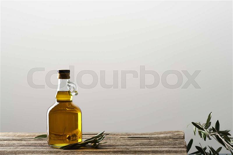 Bottle of oil and olive tree leaves isolated on grey , stock photo