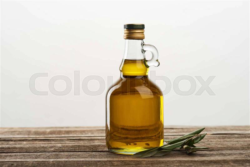 Bottle of olive oil and olive tree leaves isolated on grey , stock photo