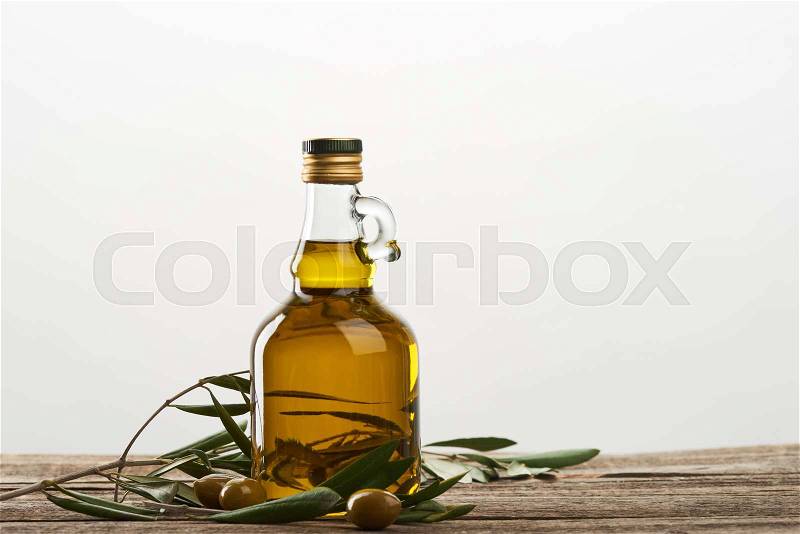 Oil bottle with olive tree leaves and olives isolated on grey , stock photo