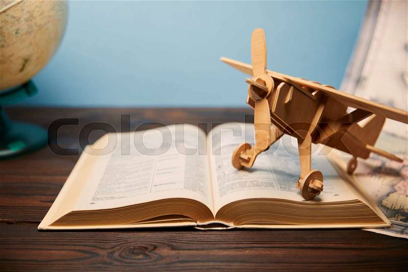 Selective focus of book and toy plane on wooden table, stock photo